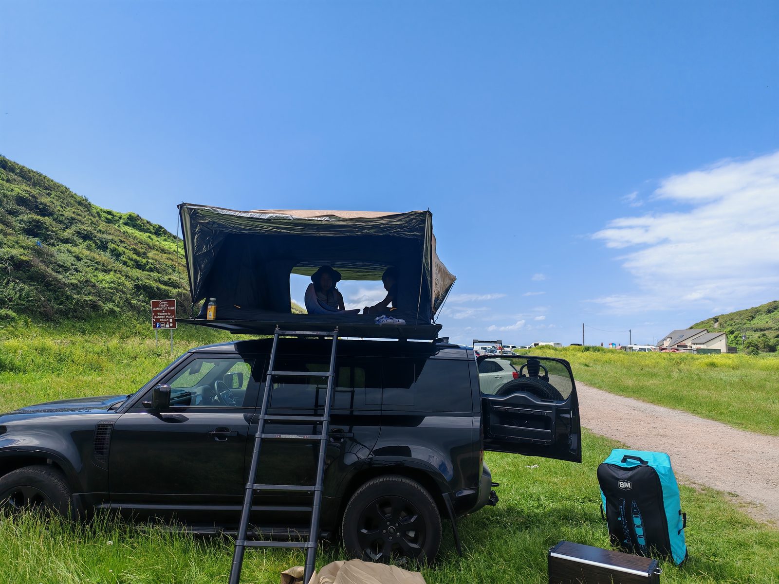 Open roof tent with sleeping area on a Defender, beach car park in Wales