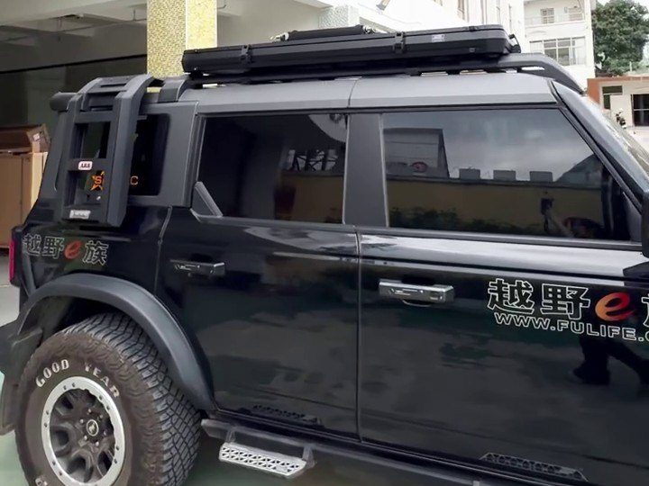 Closed roof tent on the roof rack of a black Ford Bronco