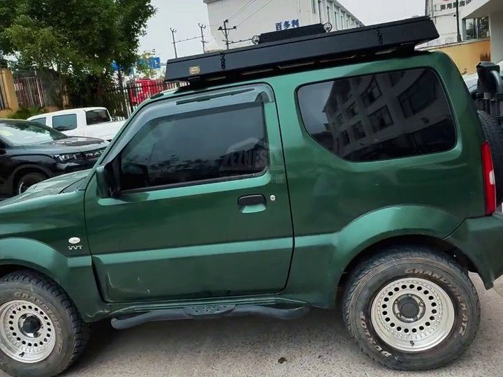 Green Suzuki Jimny with the roof tent closed on top