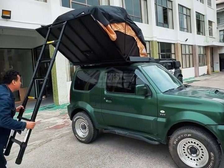 Roof tent being opened on a green Suzuki Jimny