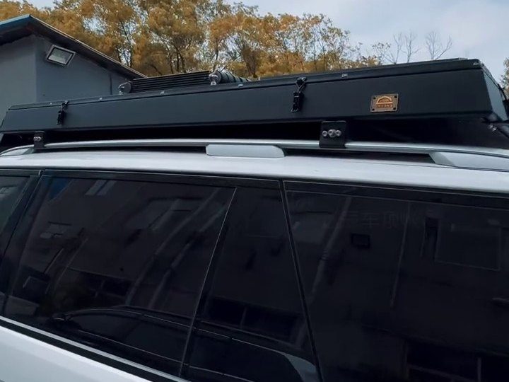 Closed roof tent lying flat on the roof rails of a white Range Rover