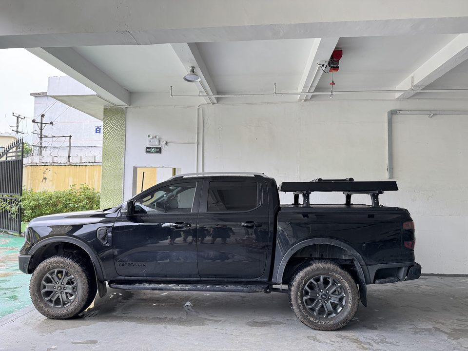 Small roof tent closed on the rack of a black Ford Ranger