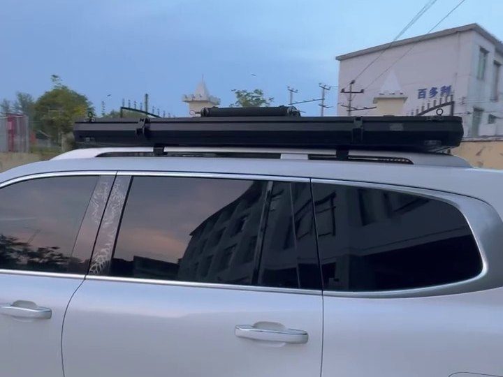 Slim closed roof tent on the roof rails of a white SUV