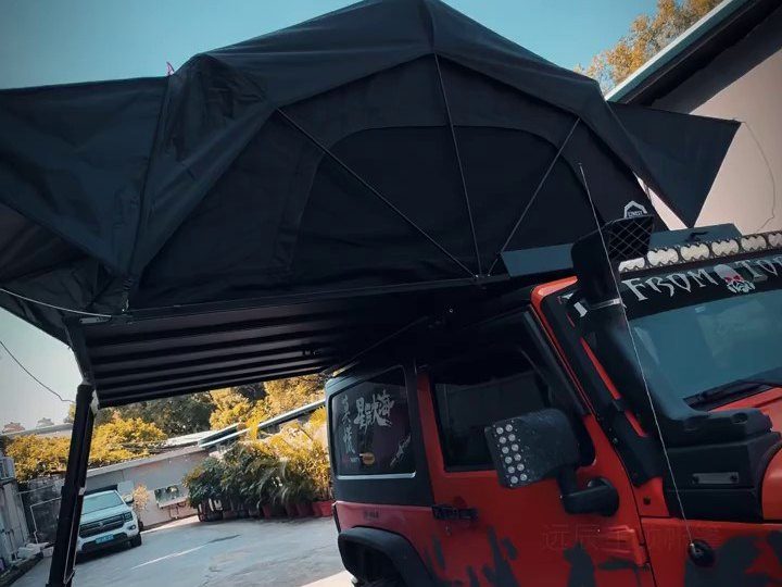 Roof tent open over a red Jeep Wrangler